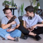 Happy talking mom and teenage son, parent and child sitting at home on the floor with pet little dog toy terrier, real friendly loving family