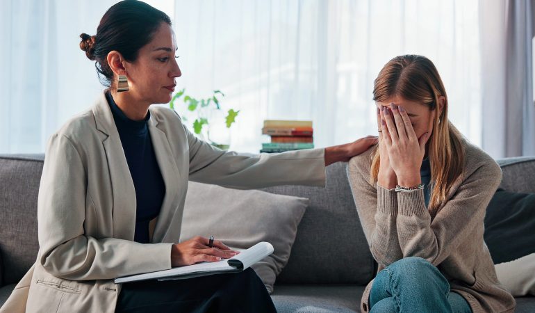 Sad, woman and comfort with psychologist for counseling, emotional support and empathy. Grief, therapist and consoling patient with depression for compassion, trauma recovery and coping assistance