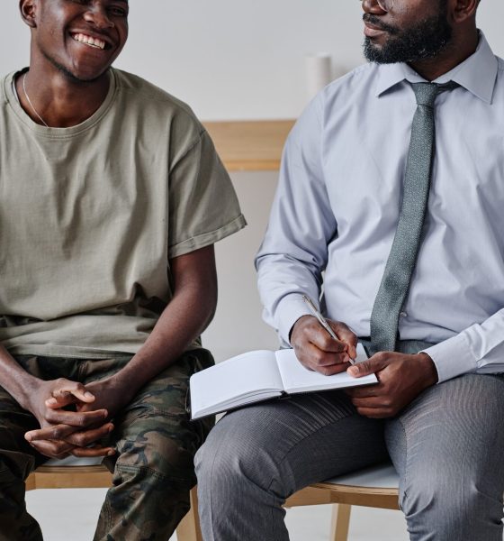 African psychiatrist talking to patient and making notes in notepad at psychology class